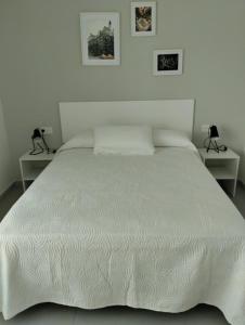 a bedroom with a white bed with two tables at Iberflat Apartamentos Alfabega in Paterna