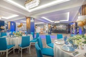 a banquet room with tables and blue chairs and a room with atainment center at Hotel City Break in Galaţi