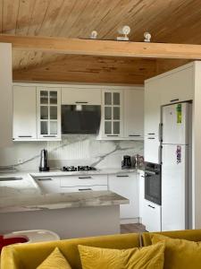 a kitchen with white cabinets and a refrigerator at Sera Pansiyon in Cıralı