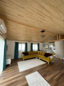 a living room with a yellow couch and wooden ceilings at Sera Pansiyon in Cıralı +109 photos