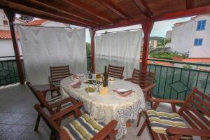 a table and chairs on a patio with a view of a balcony at Apartment Breza in Sućuraj +15 photos