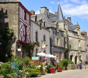 an old building with tables and umbrellas in front of it at Gîtes du Cosquer in Malguénac