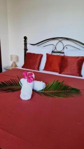 a bedroom with a red bed with red pillows and towels at Maïlly - Charmante villa T5 avec piscine - Empire House in Capesterre-Belle-Eau +32 photos