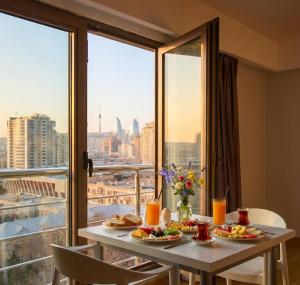 a table with plates of food and a view of the city at Diplomat Suites Hotel in Baku