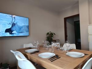 a wooden table with white chairs and a tv on a wall at Alexander Lodge in Isolaccia