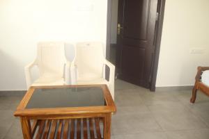 two white chairs sitting next to a wooden table at Yogi Ram Guest House in Tiruvannāmalai