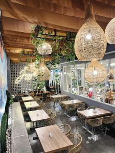 a restaurant with wooden tables and chairs and chandeliers at Hotel FortunaGrande Malioboro Yogyakarta in Yogyakarta