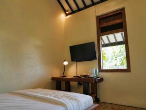 a bedroom with a bed and a flat screen tv at Omahe Kancaku in Balong