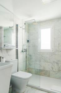 a white bathroom with a shower and a toilet at Marina Bayview Gran Canaria - Adults Only in Puerto Rico de Gran Canaria
