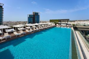 a large pool with chairs and umbrellas on a building at InterContinental Malta by IHG in St. Julianʼs