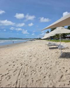 a beach with two chairs and umbrellas on it at Beira mar Flat Deluxe Nomar Carneiros Ecoliving Réveillon in Tamandaré