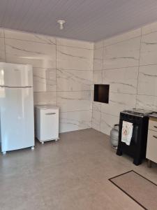 a kitchen with a refrigerator and a tv on a wall at El Tata in Arroio do Silva