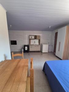 a room with a bed and a table and a kitchen at El Tata in Arroio do Silva