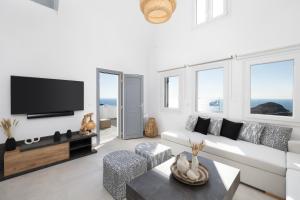 a living room with a white couch and a tv at Occhio-Nero Cycladic Private Villa with Pool & Sunset View Jacuzzi in Akrotiri