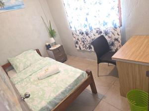a small room with a bed and a desk and a window at G&A Friendly stay in Port Vila