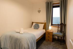 a bedroom with a bed and a chair and a window at Taftnica in Burray Village