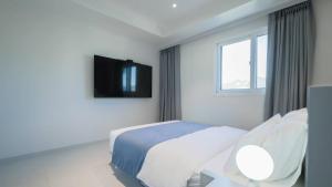 a white bedroom with a bed and a tv on the wall at The M Hotel in Seoul