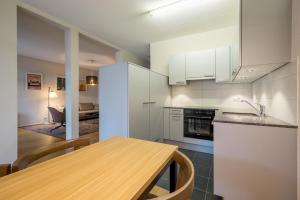 a kitchen with white cabinets and a wooden table at Apartment Harderstrasse in Interlaken