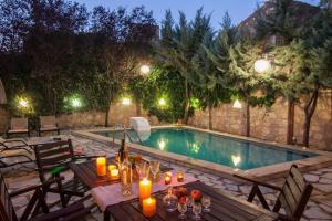 a table with candles next to a swimming pool at night at Sarris Villa in Áyios Mámas