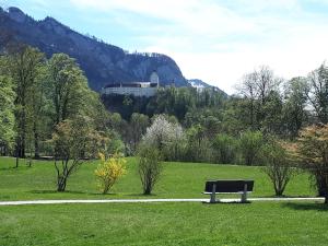 a park bench in a field with a building in the background at Bergblick Kampenwand in Aschau im Chiemgau +9 photos