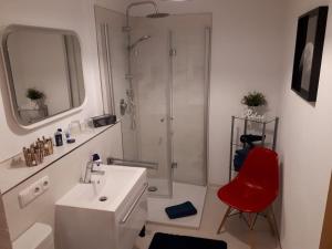 a bathroom with a shower and a sink and a red chair at Bergblick Kampenwand in Aschau im Chiemgau