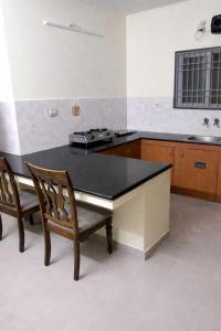 a kitchen with a black table and two chairs at Zest Homes Nugambakkam in Chennai