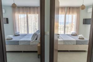 a bedroom with two beds and two windows at Symphony Suite in Panormos Rethymno +19 photos