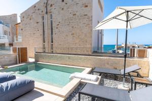 a swimming pool with an umbrella next to a building at Symphony Suite in Panormos Rethymno