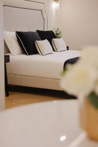 a bed with black and white pillows on it at SOFIA Suites & Rooms in Pompei