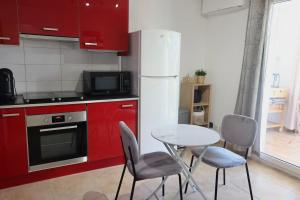 a kitchen with red cabinets and a table and chairs at Lora Apartment with Garden & Pool in Mandelieu-La Napoule