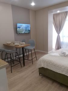 a bedroom with a bed and a table and a tv at WOODSPACE Apartment in Shchūchīnsk