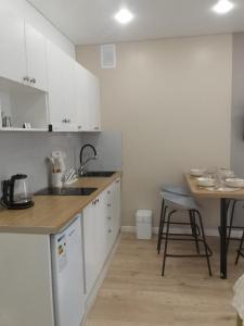 a kitchen with white cabinets and a wooden table at WOODSPACE Apartment in Shchūchīnsk