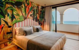 a bedroom with a large bed with a painting on the wall at Casa Indiana Hotel Boutique in Blanes