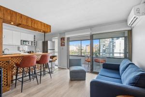 a living room with a blue couch and a kitchen at Isabel Suites Vitacura in Santiago