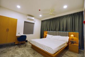 a bedroom with a bed and a chair and a window at Avenue A boutique hotel in Vijayawāda +16 photos