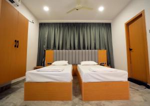 two beds in a room with a window at Avenue A boutique hotel in Vijayawāda