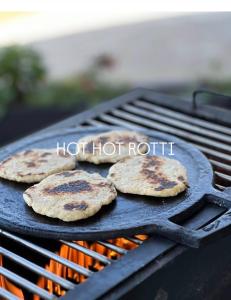three hamburgers cooking on a grill with the words hot hot roti at Pekoe House in Galaha Town