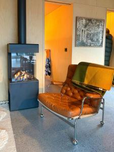 a leather couch sitting in front of a fireplace at Architect-Designed Cabin By Lake With Sauna in Homle