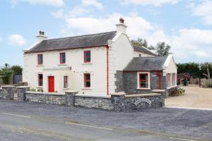 a white house with red doors on a street at Making Tracks Hostel in Portlaoise