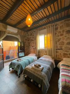 two beds in a room with a stone wall at Panorama Guesthouse in Agadir