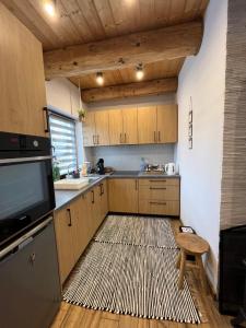 a kitchen with wooden cabinets and a large rug at Domek w lesie Sauna i Gorąca balia Wellness&Spa in Grybów