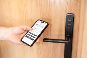 a person holding a cell phone unlocking a door at Weitnau Stays - Hotel & Hostel in Weitnau