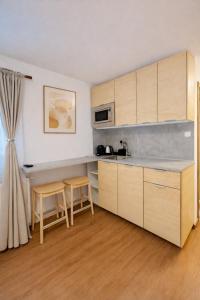 a kitchen with wooden cabinets and two stools at Apartmány Ella in Hřensko