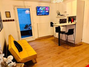 a living room with a yellow couch and a table at petit studio de bourgogne in Saint-Albain +3 photos