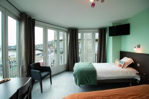 a hotel room with a bed and a desk and window at Hotel Le Richelieu in Le Tréport