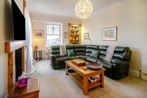a living room with a black leather couch and a table at 4 Bed in Pittenweem oc-t35090 in Pittenweem