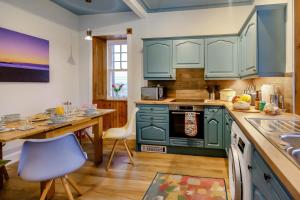 a kitchen with green cabinets and a table with a blue chair at 4 Bed in Pittenweem oc-t35090 in Pittenweem