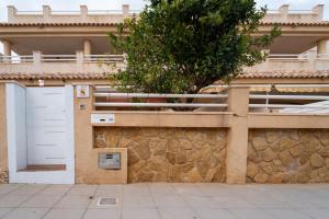 a building with a white door and a stone wall at Chalet adosado en la playa de Torre de la Horadada in Torre de la Horadada