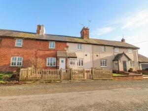 an old brick house with a wooden fence at Little Launde Cottage in Leicester