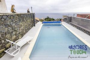 a swimming pool with a lounge chair and a swimming pool at Sunset Pool House in Feteira